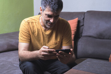 Comfort and Technology. Relaxed man on the sofa with his mobile phone.