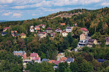 Picturesque aerial landscape view of Loket village. Colored residential houses on the slope of the mountain with ancient trees by summer sunny day. Bohemia, Sokolov, Karlovarsky Region,Czech Republic