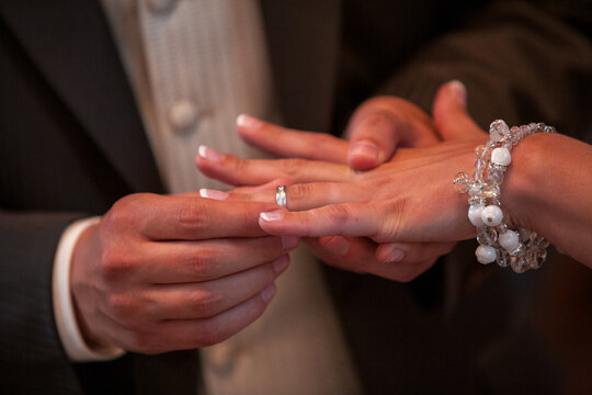 A heartfelt close-up photograph capturing the tender moment of a loving bride and groom exchanging beautiful wedding rings. The image evokes emotions of commitment and devotion, embodying the 'Marry