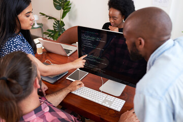 Three developers peer programming together in office, assisting peer review