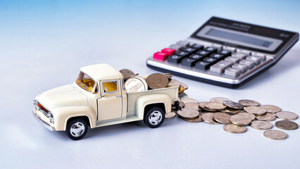 Silver coins on white truck toy with calculator in background. Business or investment concept.