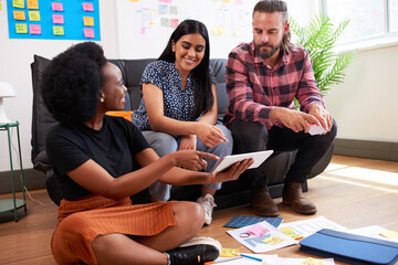 Group of diverse colleagues brainstorm together, informal meeting sit on floor