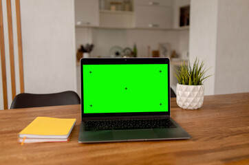 home workplace with laptop on table with empty blank green screen mockup for advertising
