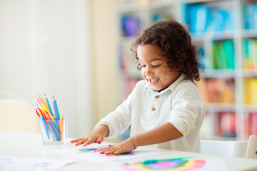 Child drawing rainbow. Paint on hands.