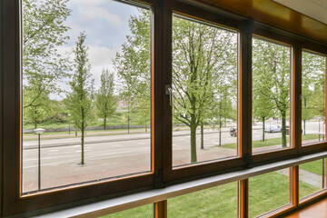 an outside view from inside a train car looking out onto the street with trees and buildings in the back ground