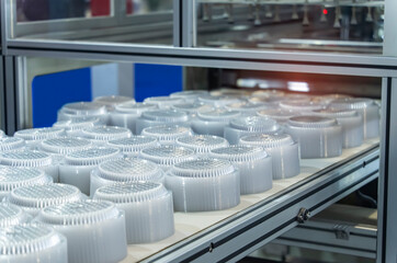 Stack of polypropylene food containers on conveyor belt of automatic plastic injection molding...