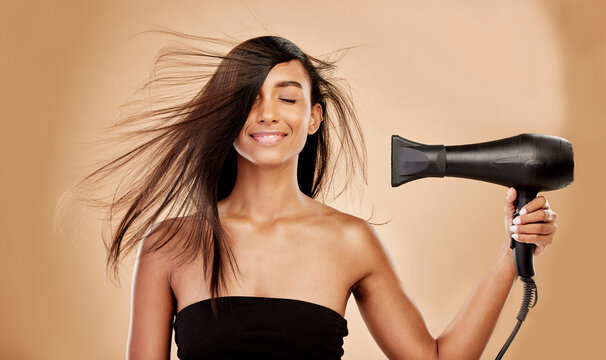 Hair, Dryer And Smile Of Woman In Studio For Beauty, Grooming And Heat Equipment On Background. Indian Female Model, Haircare And Tools With Wind For Hairstyle, Salon Appliance Or Aesthetic Treatment