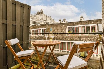 a balcony with two chairs and a table in front of a building that looks like an outdoor cafe or restaurant