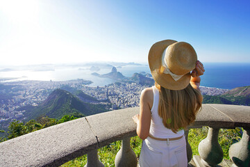 Holidays in Rio de Janeiro, Brazil. Traveler girl on Corcovado mountain looks Guanabara Bay. Beautiful young woman on Christ the Redeemer viewpoint enjoying cityscape of Rio de Janeiro, Brazil.