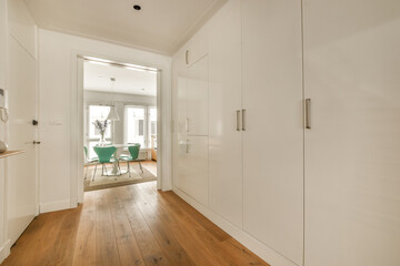 a room with white walls and wood flooring in the middle of the room there is an open door leading to another room