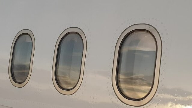 Close up of airplane exterior portholes and rivets at dusk. Pan right