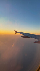 Red airplane wing seen from window view on afternoon with orange sky