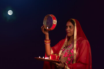 Fototapeta premium Woman looking at moon through a sieve during Karva Chauth