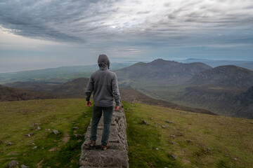 Panoramic view of typical Irish landscape, fields, sea in background. Picture taken from the top of the mountain. Hiker enjoing view after sunset
