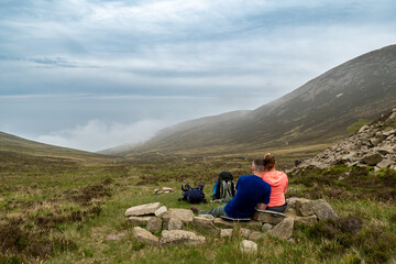 Fototapeta na wymiar Couple of hikers enjoying the view. Typical Irish mountains landscape.
