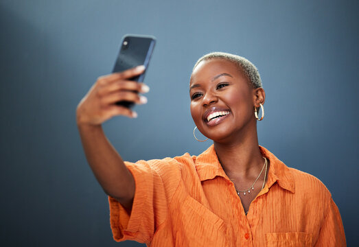 Selfie, smile and black woman in studio for photography, video call or photo on grey background. Smartphone, happy and lady social media influencer with profile picture, live streaming or blog update