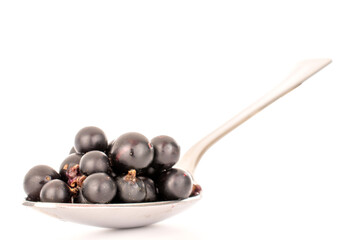 Several berries of sweet black currant with a metal spoon, macro, isolated on white background.