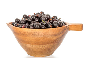 Several berries of sweet black currant in a wooden cup, macro, isolated on white background.