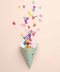 Birthday cone cap with letters on beige background. Party concept. Top view