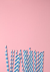 Blue paper straws on pink pastel background. Party, birthday accessories