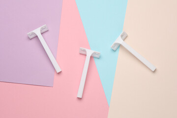 Disposable white plastic razors on pastel background. Top view. Flat lay