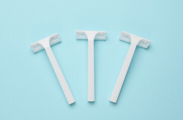 Disposable white plastic razors on blue background. Top view