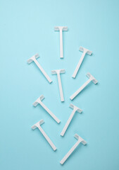 Disposable white plastic razors on blue background. Top view