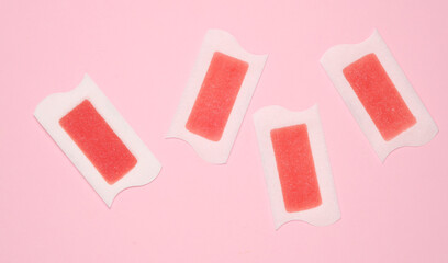 Wax strips for depilation on pink background. Top view