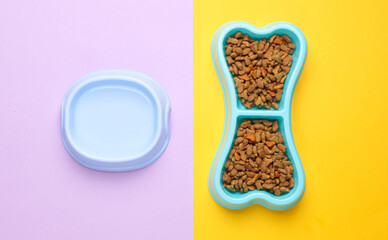 Bowl of bone-shaped dry dog food on a pastel background. Top view
