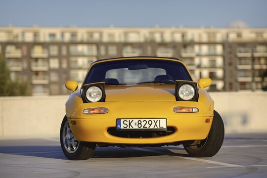 Auto mazda model mx-5   1995 r. w kolorze sun burst yellow gen N po liftingu zaparkowana na parkingu widok z zewnątrz.