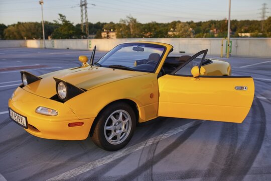 Auto mazda model mx-5   1995 r. w kolorze sun burst yellow gen N po liftingu zaparkowana na parkingu widok z zewnątrz.