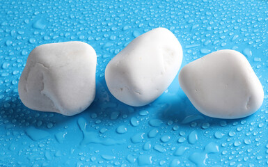 White pebbles on a blue background with water drops. spa, relaxation therapy
