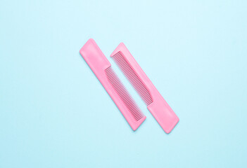 Pink plastic combs on a blue background. Beauty and fashion minimalism still life