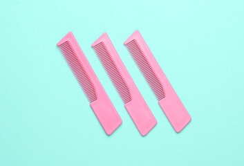 Pink plastic combs on a blue background. Beauty and fashion minimalism still life