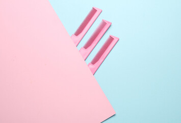 Obraz premium Pink plastic combs on a blue pink background. Beauty and fashion minimalism still life