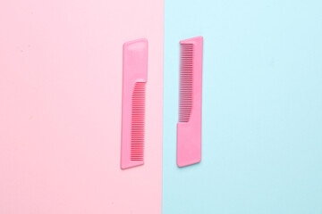Pink plastic combs on a blue pink background. Beauty and fashion minimalism still life