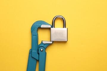 Metal adjustable wrench holding lock on yellow background.