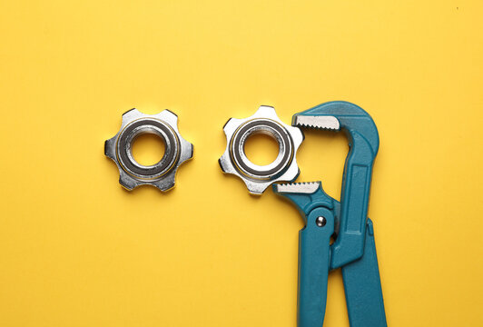 Metal adjustable wrench with nut on yellow background.