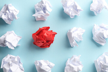 Crumpled white and red balls of paper on a blue background. Leadership, uniqueness, business concept