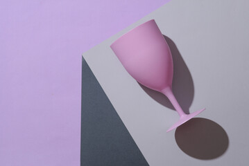 Plastic goblet on the corner of gray cube. Optical geometric illusion. Creative layout. Minimalism