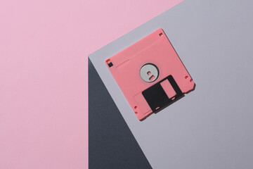 Pink Floppy disk on the corner of gray cube. Optical geometric illusion. Creative layout. Minimalism. Retro 80s