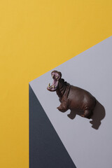 Toy hypopotamus on the corner of gray cube. Optical geometric illusion. Creative layout. Minimalism