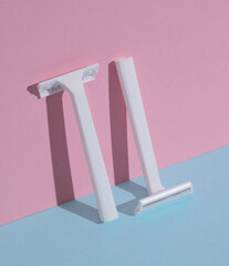 White razors on a blue-pink background. Beauty concept. Creative layout, minimalism