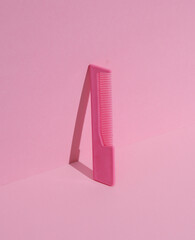 Plastic comb on pink pastel background. Beauty concept. Creative layout, minimalism