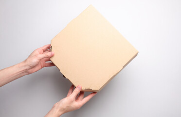 Hands holding craft blank pizza box on gray background. Top view.