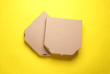 Two empty craft cardboard pizza boxes on yellow background. Template for design. Top view