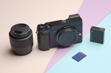 Photographer's equipment. Modern digital mirrorless camera with lens, battery and sd memory card on...