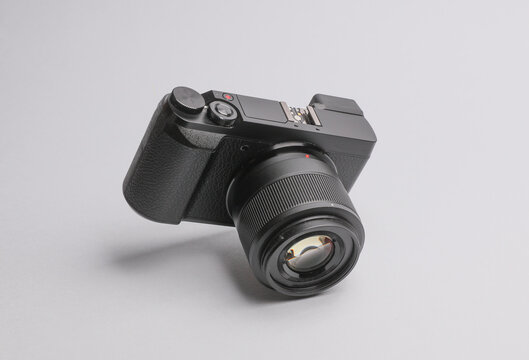 Modern digital mirrorless camera with lens soaring on gray background