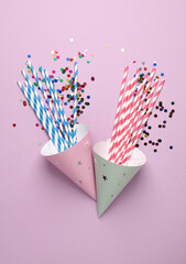 Birthday cone hats with party accessories on pink background. Top view