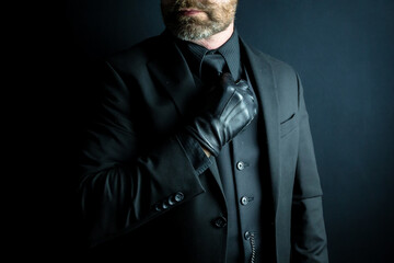 Fototapeta premium Portrait of Gentleman in Dark Suit and Leather Gloves. Handsome Model Looking Cool.
